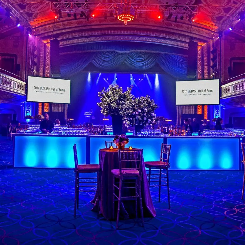 A spacious room illuminated by blue lighting, featuring several tables arranged throughout the area.
